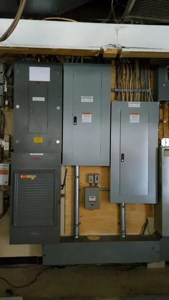 A bank of gray electrical panels and disconnects in a basement
